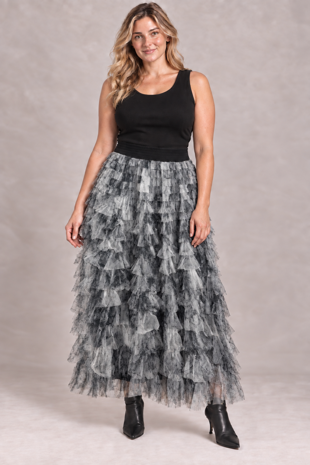 Model wearing a tiered mesh maxi skirt with a black vest top and ankle boots
